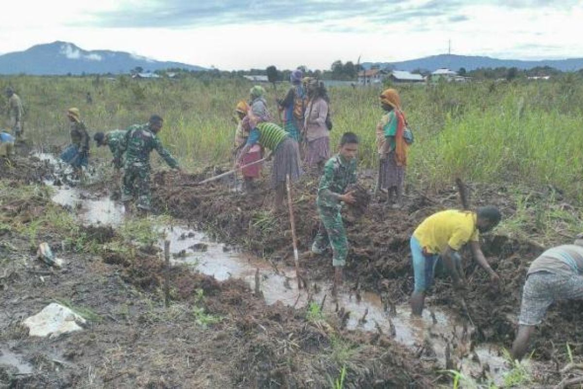 Babinsa Waghete membaur dengan warga bersihkan parit