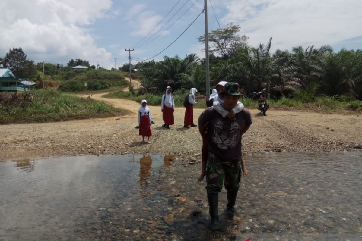 Prajurit TNI ini gendong anak sekolah menyebrangi Sungai