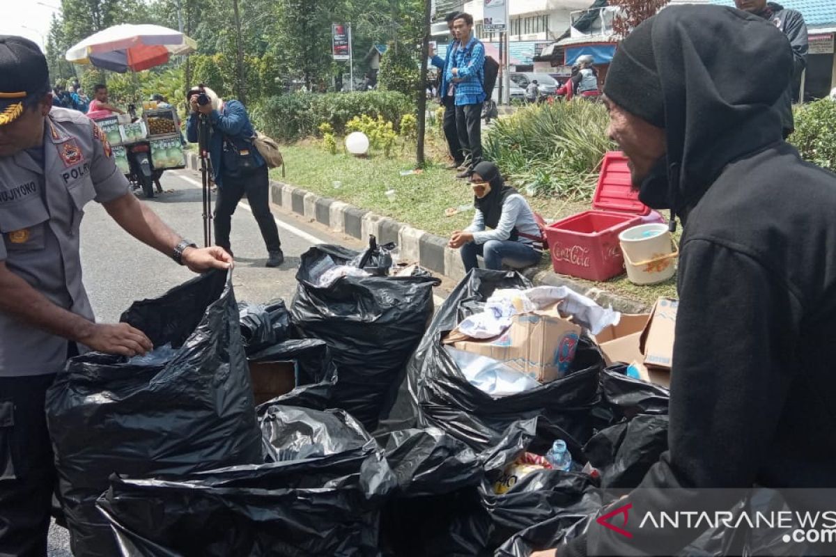 Mahasiswa dan polisi memungut sampah selesai aksi demo