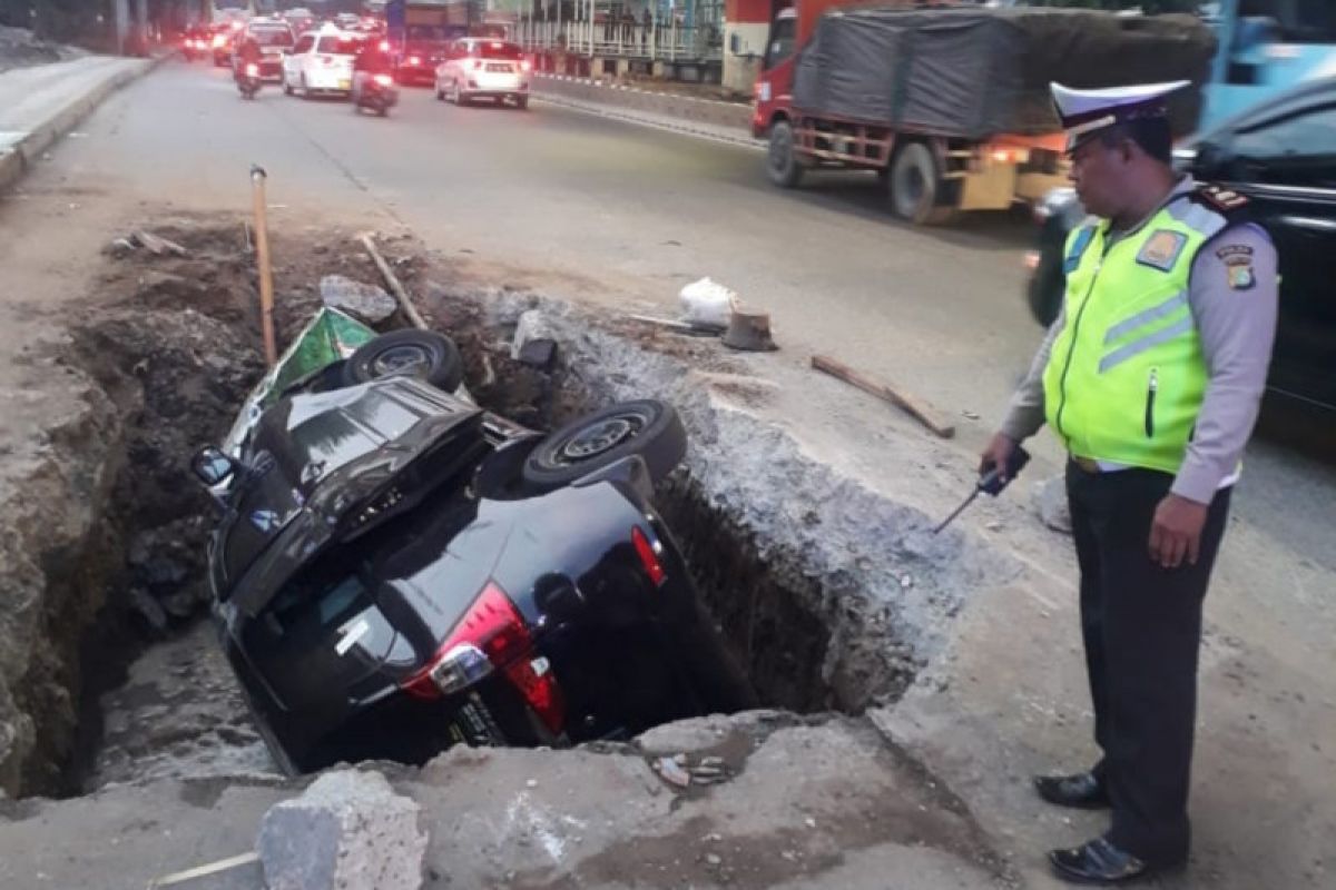 Tak hati-hati, mobil pribadi dan pengendaranya terperosok lubang galian jalan