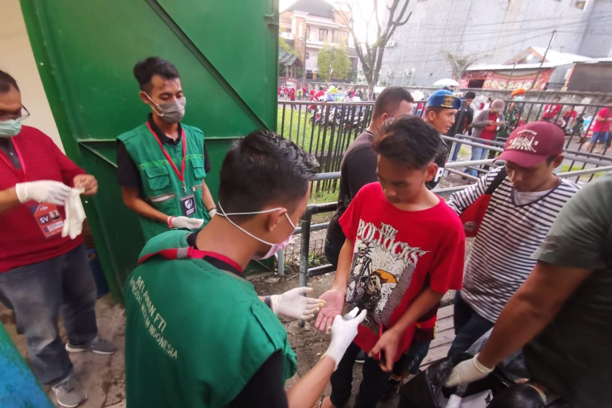 Relawan  semprotkan hand sanitizer ke tangan penonton pada laga PSM vs Barito