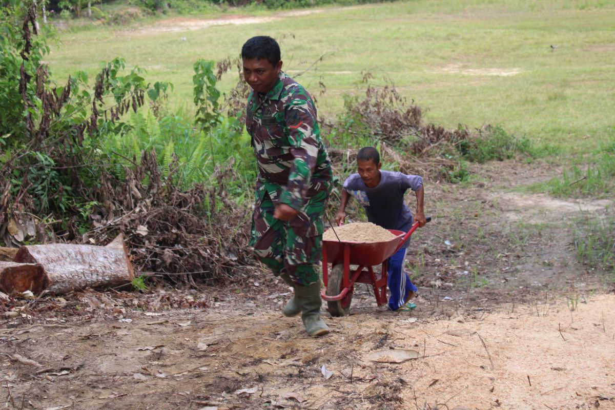 Anggota Satgas dan warga gotong royong pindahkan material bangunan