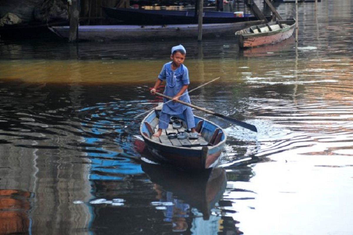 Anak berperahu menembus banjir saat Idul Fitri