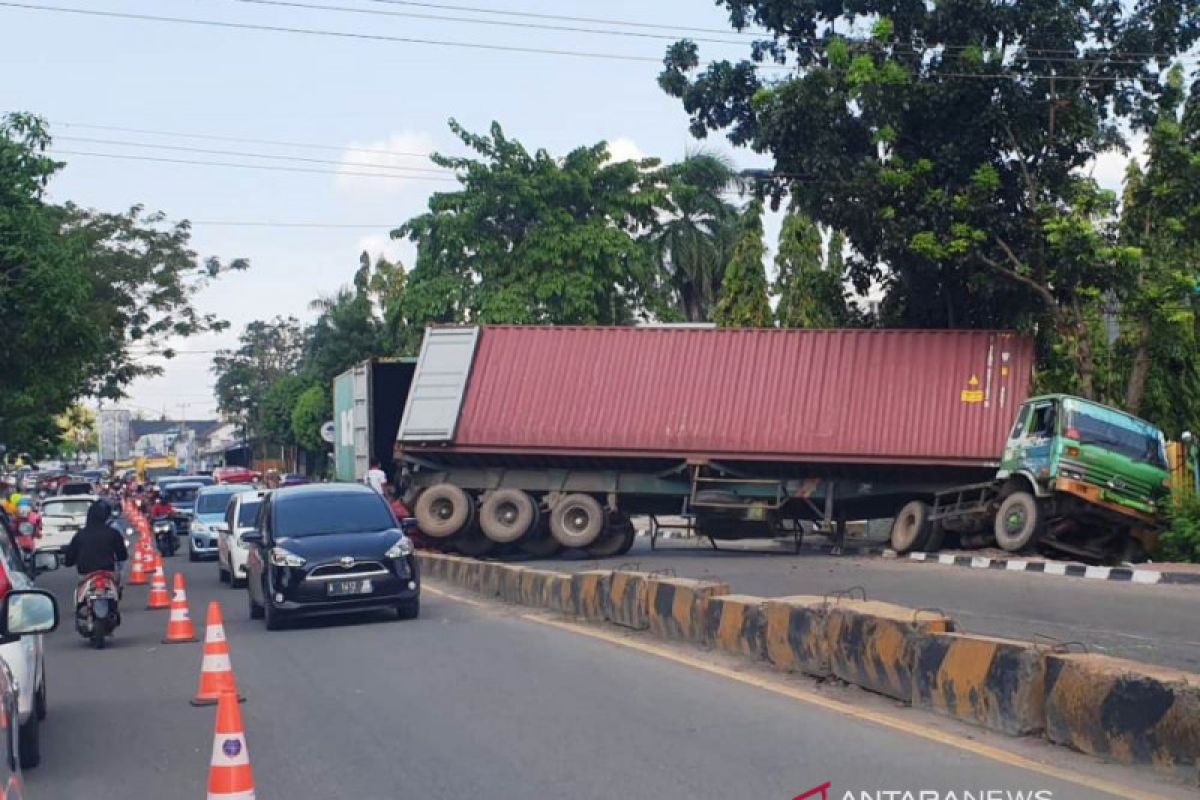 Truk peti kemas terguling di tengah jalan