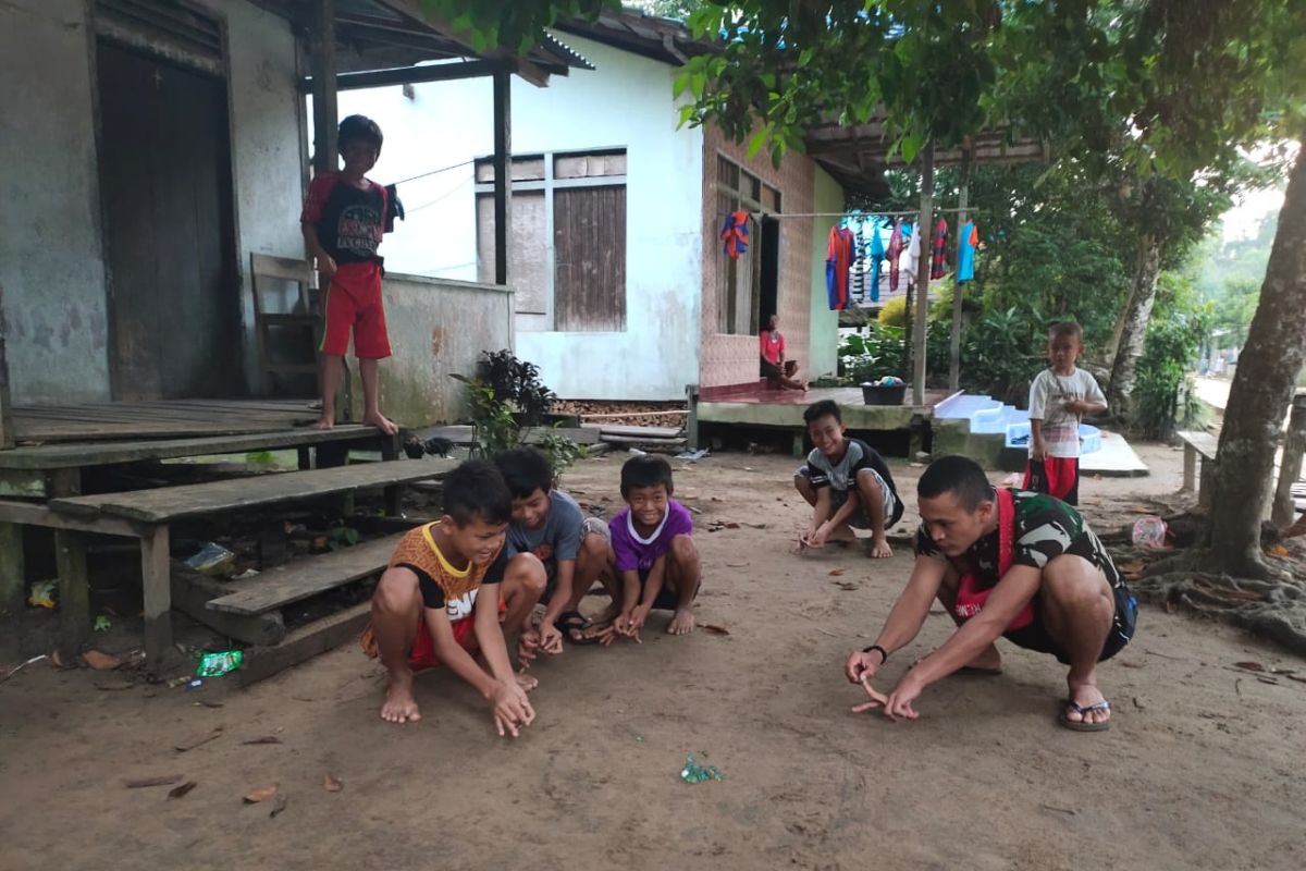 Anggota TMMD ikut bermain kelereng bersama anak-anak