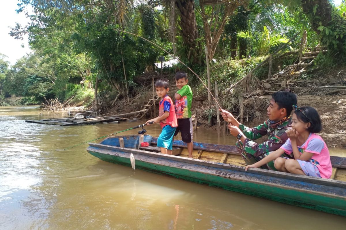 Personel TMMD akrab memancing bersama anak-anak di sungai