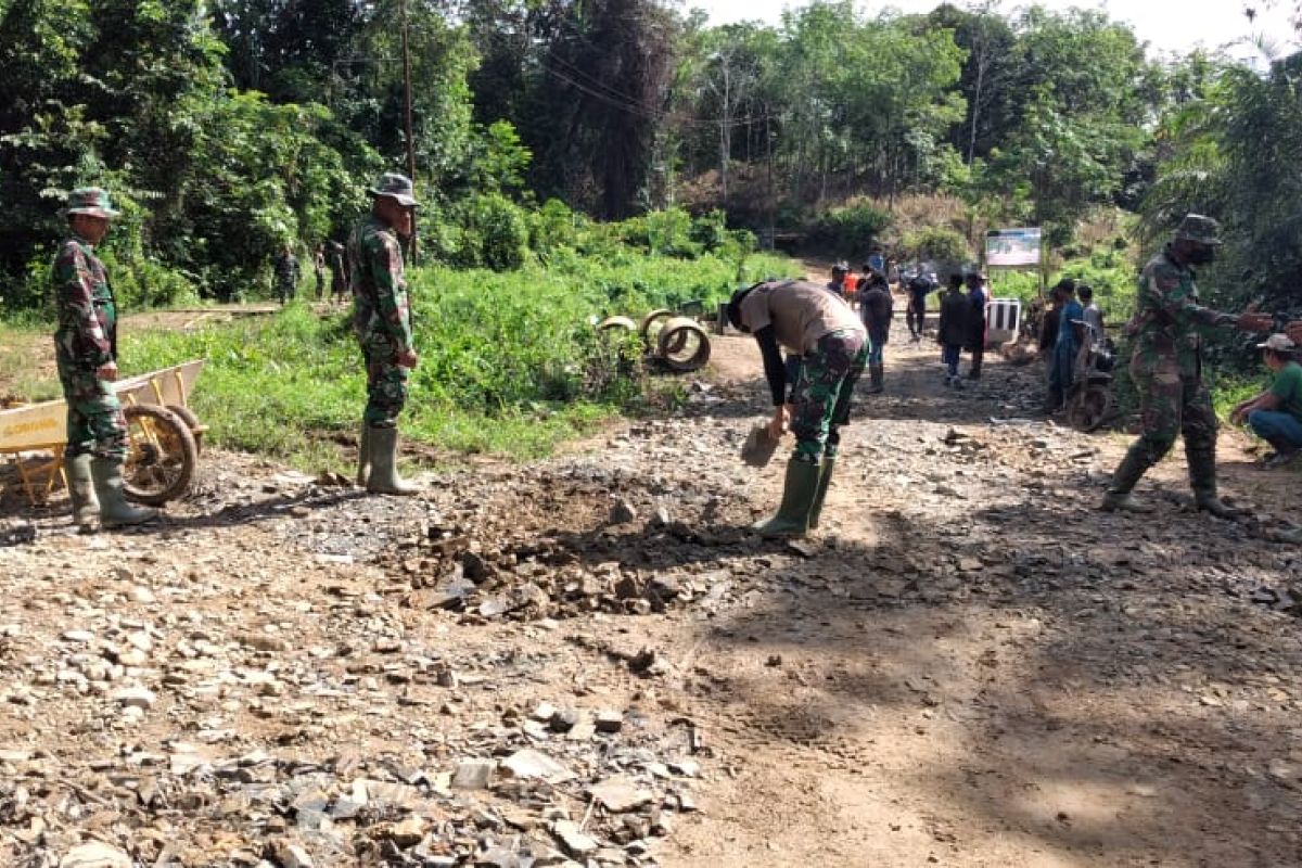 Anggota satgas TMMD dan warga bahu membahutimbun jalan