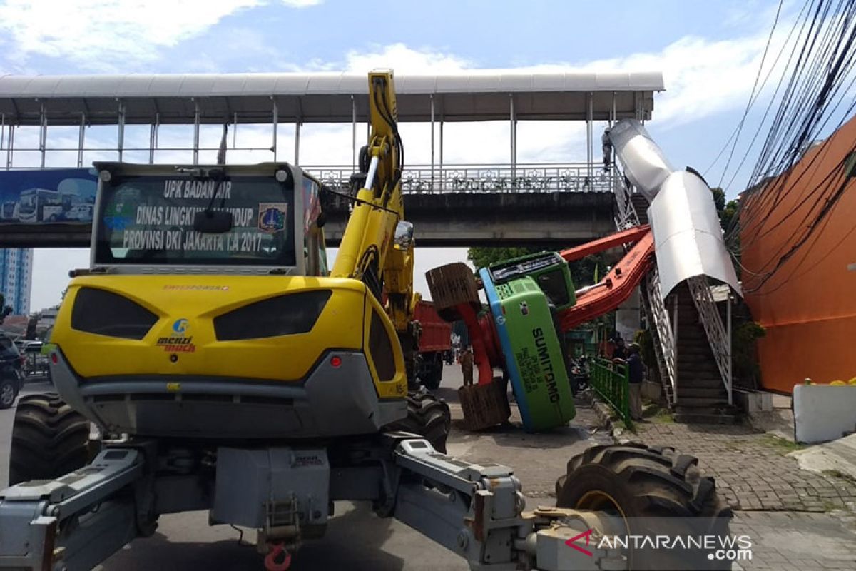 Hendak dipindahkan ke mobil pengangkut sebuat alat berat terguling timpa pagar JPO