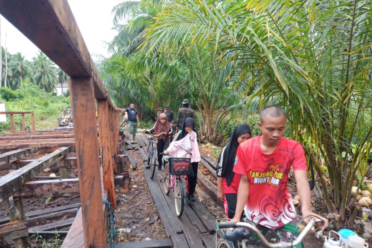 Anggota Satgas TMMD bantu warga menyeberangi jembatan kayu