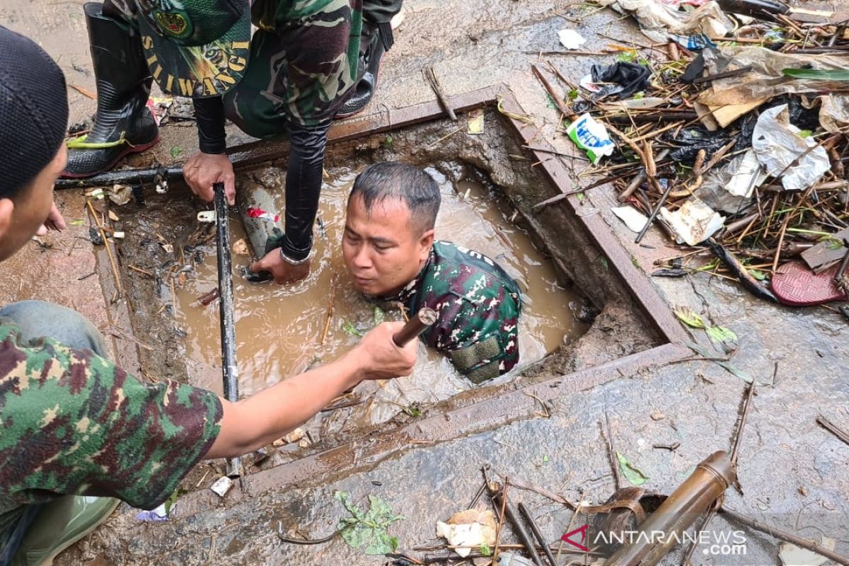 Anggota TNI menyelami parit untuk membersihkan sampah di Sumedang