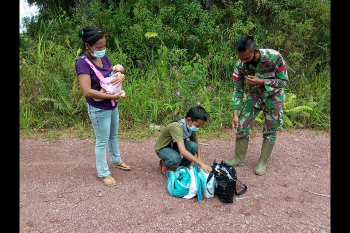 Seorang ibu membawa balita melintas jalur ilegal di batas RI-Malaysia di Badau