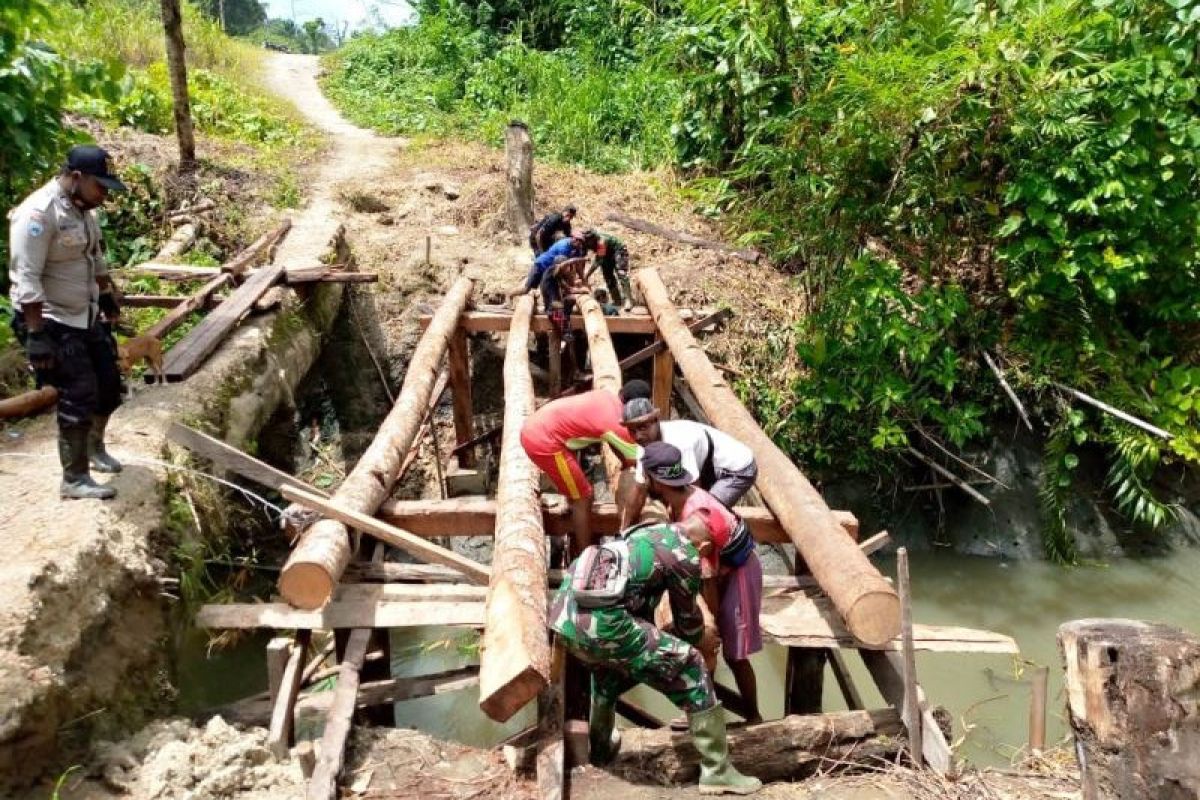 Babinsa Koramil Yaptim-Bhabinkamtibmas gotong royong perbaiki jembata kayu