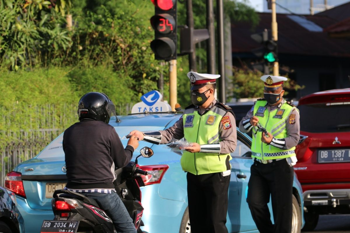 Polantas Polda Sulut membagikan masker kepada pengguna jalan