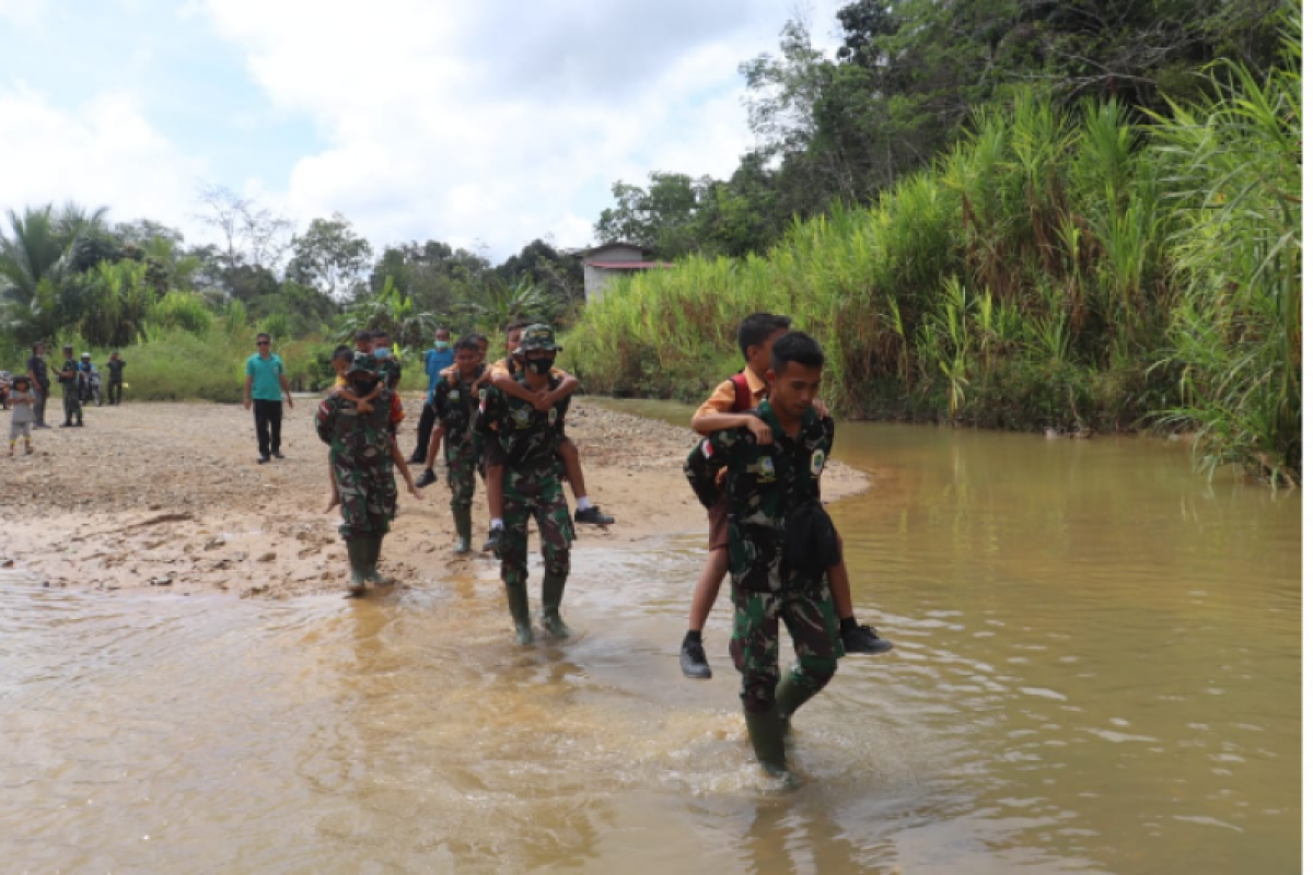 Personil Satgas TMMD gendong anak-anak SD  bantu seberangi sungai