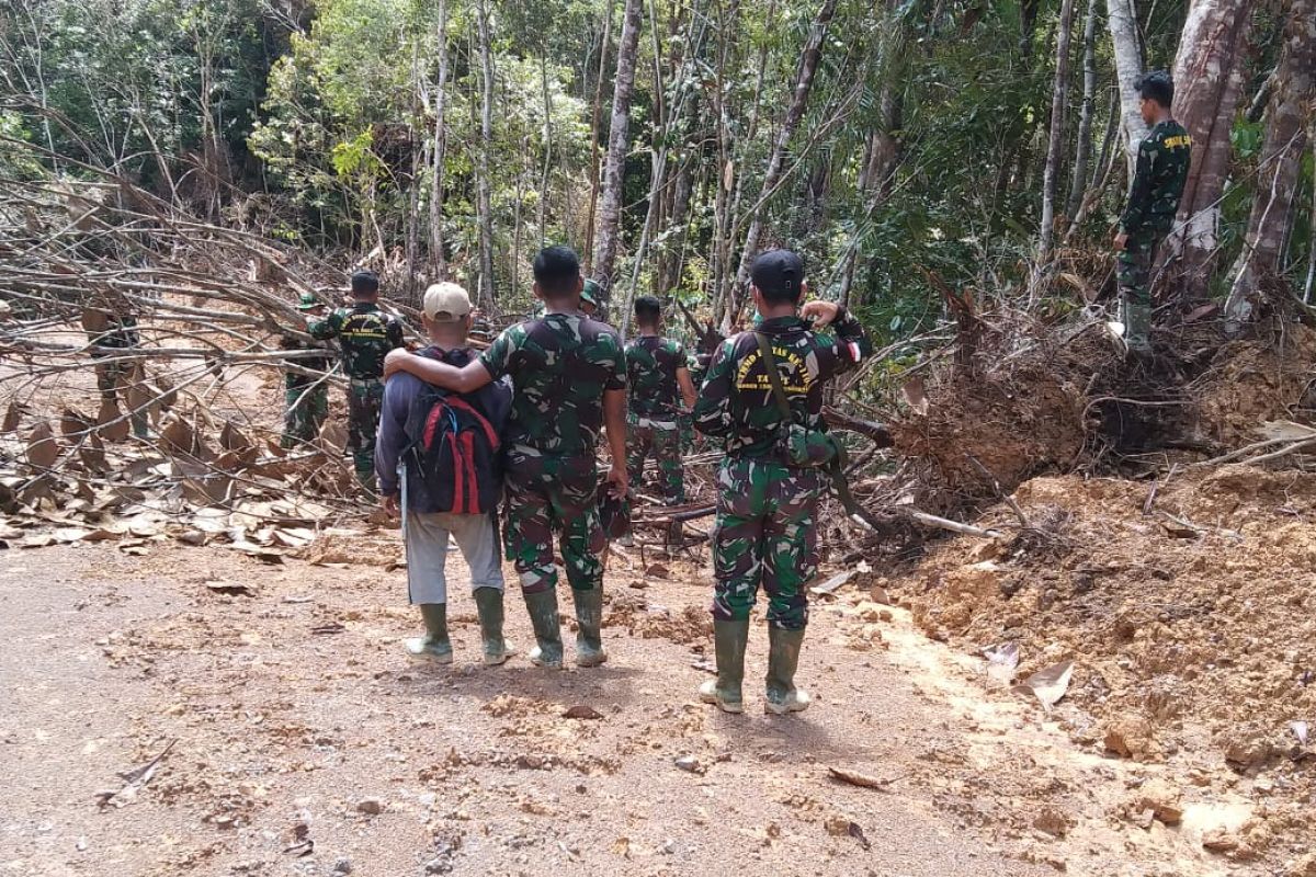 Anggota Satgas TMMD Kodim 1206/PSB membersihkan kayu tumbang di jalan