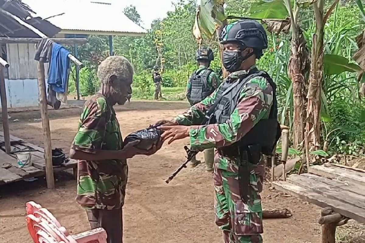 Indonesian soldiers share bags of rice with native Papuans