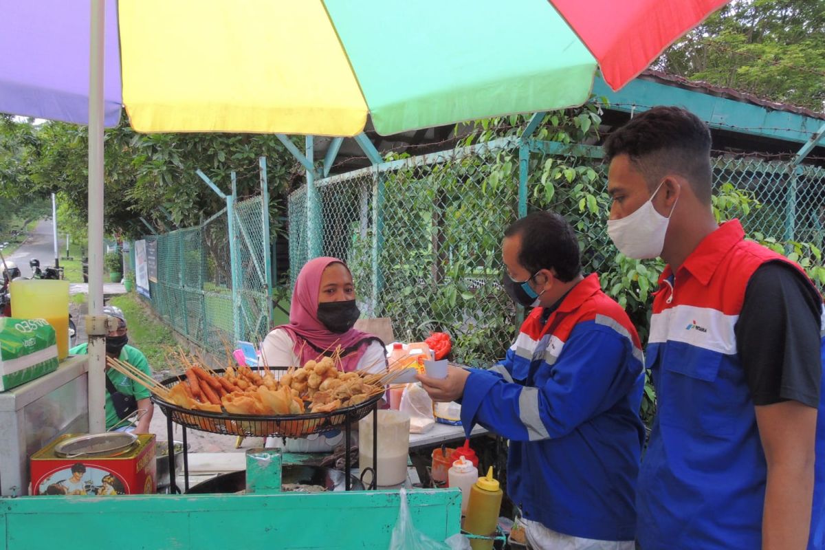 Pekerja muda Pertamina bagi paket bantuan ke pedagang asongan Lapangan Merdeka