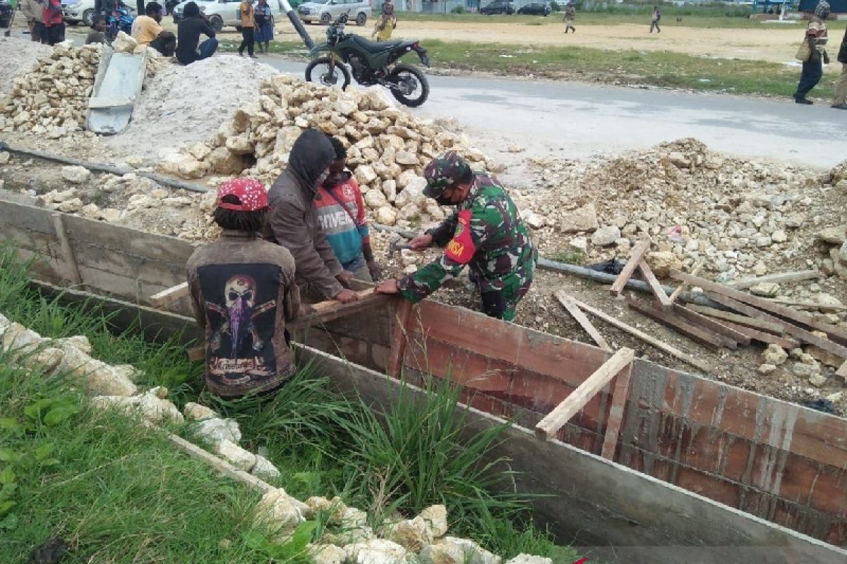 Personel TNI bersama warga mengecor bahu jalan poros Paniai Timur