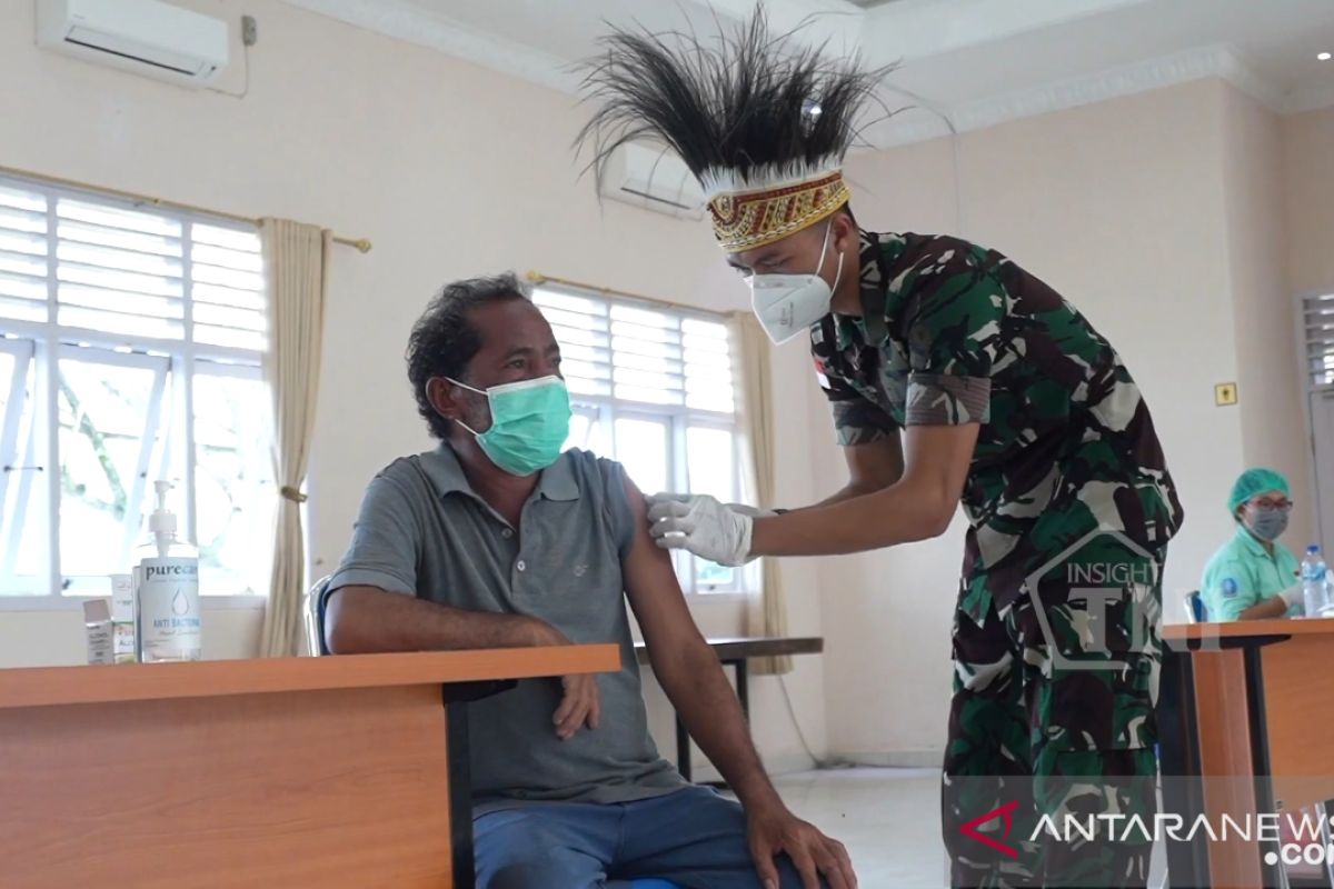 Prajurit TNI gunakan hiasan kepala khas Papua gelar vaksinasi warga