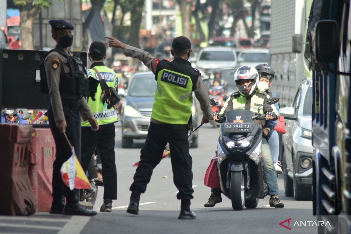 Police officers divert motorcyclists away from Cileunyi toll gate