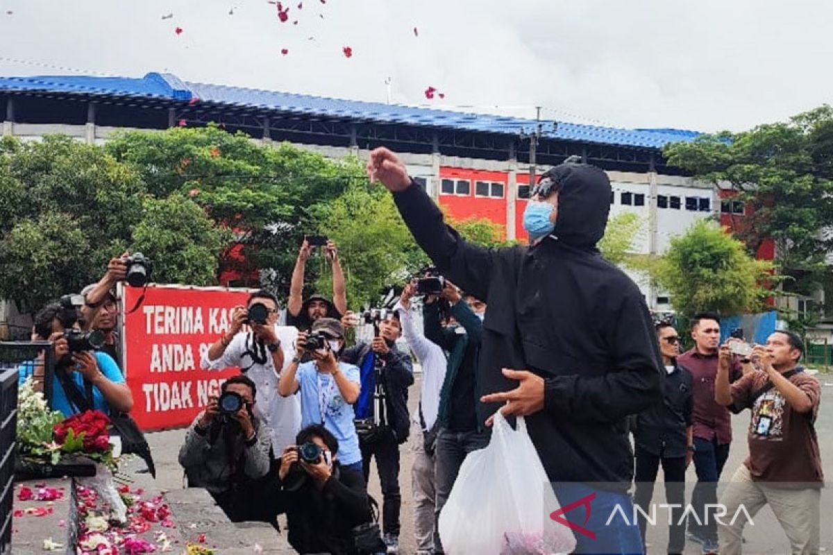 Aremania tabur bunga di depan patung singa Stadion Kanjuruhan Malang