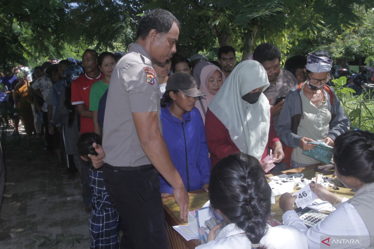 Warga mengantre untuk dapat sembako dalam pasar murah di Kupang