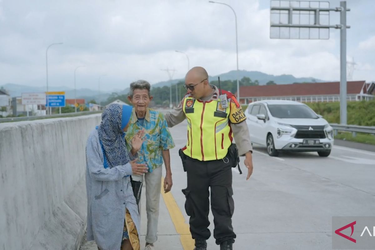 Sepasang lansia berjalan kaki di pinggir jalan tol