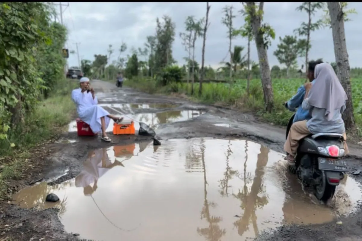 Aksi warga Keruak Lotim memancing ikan di genangan air jalan rusak