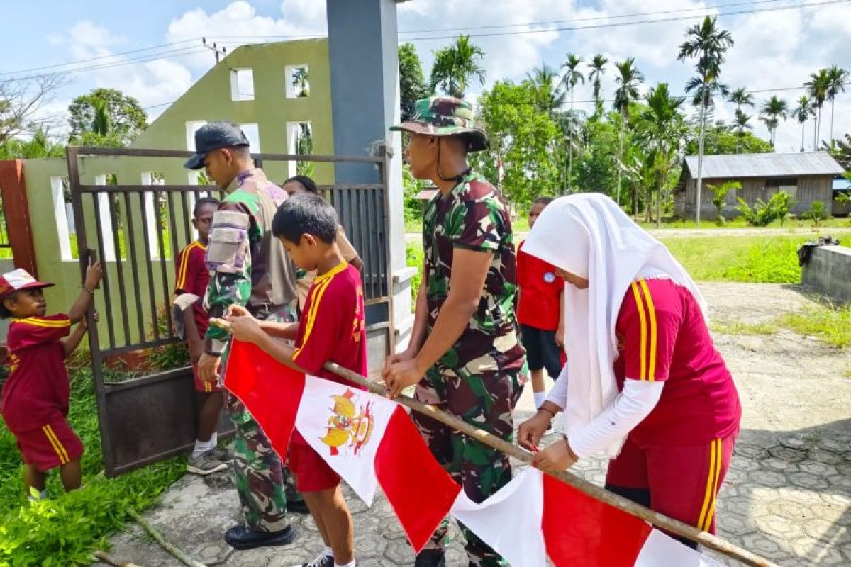 Yonif 122/TS bersama siswa SD Keerom pasang bendera Merah Putih