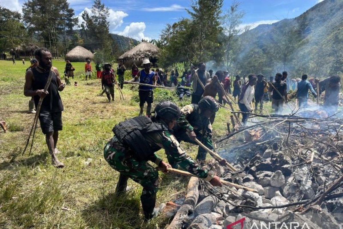 Prajurit TNI Satgas Yonif 511/DY mendukung prosesi "bakar batu" sambut Natal