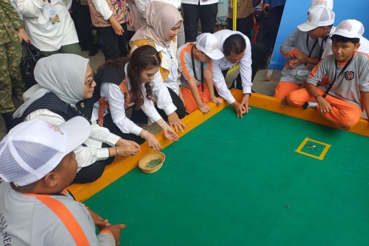 Bộ trưởng Phụ nữ và Bảo vệ Trẻ em Arifatul Choiri Fauzi (đội hijab xám) và Phu nhân thứ hai Selvi Ananda (bên phải) chơi trò chơi bi truyền thống trong lễ kỷ niệm Ngày Trẻ em Quốc gia lần thứ 42 tại Tanjungpinang, Quần đảo Riau, ngày 23/7/2026 (ANTARA/Oge).