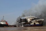 BANJARMASIN, 26/9 - MARINA NUSANTARA TERBAKAR - Petugas pemadam menyemprotkan air ke kapal Marina Nusantara yang terbakar di tengah perairan Sungai Barito Kalimantan Selatan setelah bertabrakan dengan tongkang batubara Pulau Tiga dengan korban tiga orang meninggal dan 26 lainnya masih kritis, Senin (26/9).  Kapal berlayar dari pelabuhan Tanjung Perak Surabaya menuju pelabuhan Trisakti Banjarmasin berpenumpang 443 orang dan angkutan kendaraan serta sembako. Foto ANTARA/Herry Murdy Hermawan/B