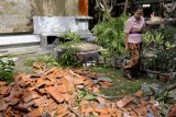 Denpasar (Antara Bali) - Seorang pegawai membawa sesajen di samping reruntuhan genteng SMK 2 Sidakarya yang rontok akibat gempa di Denpasar, Bali, Jumat (14/10). Proses belajar mengajar di beberapa sekolah yang rusak akibat gempa 6,8 SR masih belum berjalan bahkan diliburkan hingga dua hari. FOTO ANTARA/Nyoman Budhiana/11.