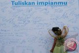 Seorang anak menulis di selembar kain saat berlangsung Jalan Sehat Keluarga frisian Flag di halaman MOG, Malang, Jawa Timur, Minggu (8/4). Kegiatan yang diikuti ribuan peserta dengan melepaskan balon impian tersebut merupakan kampanye "Berani Bermimpi Raih Esokmu" yang diadakan di beberapa kota di Indonesia. FOTO ANTARA/Ari Bowo Sucipto/12