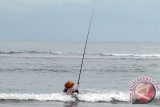 Nelayan pancing di Pantai Panjang harus berjibaku dengan ombak dan arus laut. Ia pun mengenakan ban sebagai bantuan alat keamanan. (foto ANTARA/triono subagyo)