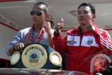 Petinju Indonesia asal Kalbar, Daud Cino Yordan (kiri) bersama Pelatihnya, Damianus Yordan, memegang sabuk kemenangan sesaat setelah tiba di Bandara Supadio, Kabupaten Kubu Raya, Kalbar, Senin (7/5). Daud Cino Yordan tiba di Pontianak dengan membawa sabuk kemenangan atas prestasinya yang telah berhasil menjadi juara dunia kelas bulu versi International Boxing Organization (IBO), setelah menang KO pada ronde kedua atas Petinju Filipina, Lorenzo Villanueva di Marina Bay Sands, Singapura pada Sabtu (5/5). FOTO ANTARA/Victor Fidelis Sentosa