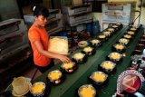 Seorang pekerja menuangkan taburan keju ke adonan Kue Bingke Berendam, di tempat usaha rumahan (home industry) Al Fajar, di Jalan Adisucipto, Pontianak, Kalbar, Senin (23/7). Memasuki bulan ramadhan, Kue Bingke Berendam Al Fajar yang merupakan penganan khas Pontianak dan dijual seharga Rp10 ribu hingga Rp16 ribu per buah tersebut, mengalami peningkatan produksi menjadi lima kali lipat karena banyaknya permintaan. (ANTARA/Jessica Helena Wuysang) 