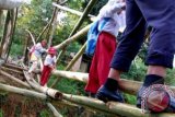 Pelajar SD bersama orangtuanya meniti jembatan bambu menyeberangi Sungai Batang Sungkai saat berangkat ke sekolah di Kel. Lambung Bukit, Kec.Pauh, Padang, Sumbar, Selasa (23/10). Jembatan bambu hasil gotong-royong masyarakat tersebut terpaksa dibangun secara sederhana karena putusnya akses jembatan permanen dari Kelurahan Kapalo Koto ke Lambung Bukit pasca banjir bandang beberapa waktu lalu. FOTO ANTARA/Iggoy el Fitra/Koz/pd/12.