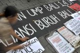 Denpasar (Antara Bali) - Seorang pengunjukrasa memajang tulisan di pintu masuk Kantor Gubernur Bali untuk menyikapi besarnya upah minimum provinsi (UMP) di Denpasar, Kamis (6/12). Pengunjukrasa gabungan Aliansi Jurnalis Independen (AJI) dan Aliansi Buruh Bali menuntut revisi UMP sebesar Rp1,181 juta menjadi Rp1,4 juta. FOTO ANTARA/Nyoman Budhiana/nym/2012.