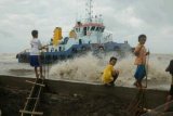 Makassar (Antara Bali) - Sejumlah anak melihat kapal penarik (tugboat) yang terseret gelombang di Pantai Tanjung Merdeka, Makassar, Sulsel, Rabu (9/1). Kapal tersebut terseret arus gelombang hingga ke bibir pantai. Berdasarkan data stasiun radio pantai Makassar, gelombang laut di perairan Makassar dalam beberapa waktu terakhir mencapai tiga meter. FOTO ANTARA/Sahrul Manda Tikupadang/nym/2013.