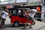 Medan (Antara Bali) - Turis yang juga peserta Reli Bajaj mendorong kendaraannya saat berangkat di Medan, Sumut, Minggu (13/1). Petualangan yang diberi nama "Bajaj Rally" tersebut diikuti sedikitnya 75 turis dari berbagai negara dalam konvoi 27 unit kendaraan roda tiga dengan melintasi jalan lintas barat Sumatera dilanjutkan ke Pulau Jawa dan Bali dalam waktu dua minggu. FOTO ANTARA/Septianda Perdana/nym/2013.