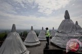 Petugas keamanan melintas di antara stupa yang ditutup mantel di objek wisata Candi Borobudur, Magelang, Jawa Tengah, Sabtu (12/1). Sebanyak 43 stupa teras dan 1 stupa induk ditutup mantel terpaulin sebagai antisipasi dampak material vulkanik dalam simulasi mitigasi bencana erupsi Gunung Merapi yang berlangsung dari 10 hingga 14 Januari 2013. FOTO ANTARA/Sigid Kurniawan