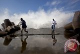 Dua wistawan berlari ketika ombak besar menghantam pemecah gelombang di Pantai Glagah, Kulon Progo, Yogyakarta, Minggu (13/1). Badan Meteorologi, Klimatologi, dan Geofisika memperkirakan tinggi gelombang laut selatan Daerah Istimewa Yogyakarta hingga 17 Januari 2013 antara 2 hingga 4 meter sebagai imbas dari pengaruh badai "Narelle". FOTO ANTARA/Sigid Kurniawan/ss/pd/13