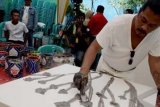 Sidoarjo (Antara Bali) - Pelukis Holis Satriawan menyelesaikan lukisannya yang berbahan dasar warna dari lumpur lapindo saat pemecahan rekor MURI (Museum Rekor Indonesia) di kawasan Porong, Sidoarjo, Jatim, Selasa (12/2). Holis Satriawan berusaha memecahkan Guinnes World Records dan Rekor MURI dalam hal melukis ekspresionis tercepat, dan terbanyak dengan membuat 100 lukisan dalam waktu 9 jam. FOTO ANTARA/Dwi Agus Setiawan/nym/2013.