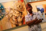 Jakarta (Antara Bali) - Seniman Bali, Made Romi Sukadana berdiri di depan lukisan karyanya yang di gelar di Lobby Graha Bakti Budaya, Taman Ismail Marzuki, Jakarta, Rabu, (12/2). Pameran bertajuk "Hidden Connections II" ini menampilkan barong, rangda, penari, wayang yang dilukis di atas kardus yang disandingkan dengan gambaran kebudayaan modern seperti Superman, Starbucks, coca cola, yang menceritakan kondisi sosial Bali saat ini. FOTO ANTARA/Teresia May/nym/2013.