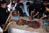 Surabaya (Antara Bali) - Sejumlah seniman dan komunitas musik Surabaya menabur bunga saat berziarah ke Makam WR Soepratman, Surabaya, Minggu (10/3). Kegiatan yang diwarnai upacara pengibaran bendera tersebut untuk memperingati Hari Musik Nasional Ke-10. FOTO ANTARA/Eric Ireng/nym/2013.