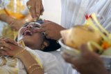 Denpasar (Antara Bali) - Seorang perempuan Bali mendapat gosokan kikir pada giginya saat ritual "Metatah" atau potong gigi masal di Puri Satria Denpasar, Bali, Senin (18/3). Ritual yang diikuti 850 umat Hindu yang sudah menginjak dewasa itu diyakini dapat menghilangkan 6 sifat buruk manusia dengan cara meratakan 6 gigi atas. FOTO ANTARA/Nyoman Budhiana/nym/2013.