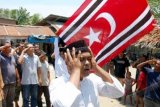 Aceh Utara (Antara Bali) - Sejumlah warga mantan kombatan Gerakan Aceh Merdeka (GAM) menghormati bendera Aceh bulan bintang dibarengi alunan azan pada upacara pengibaran bendera Aceh di Desa Alue Keude Klep, Kecamatan Tanah Pasir, Aceh Utara, Provinsi Aceh, Kamis (28/3). Bendera bulan bintang dan logo burak singa simbol kebesaran GAM yang sudah menjadi bendera dan lambang Aceh menggantikan Pancacita, pasca disahkannya Qanun (Perda) Nomor 3 Tahun 2013 tentang Bendera dan Lambang Aceh. FOTO ANTARA/Rahmad/nym/2013.