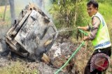 Petugas menyiram mobil yang dibakar akibat bentrok massa dari dua Lembaga Swadaya Masyarakat (LSM) yang berbeda di wilayah Rengasdengklok, Karawang, Jabar, Selasa (26/3). Satu unit mobil dan lebih dari enam unit sepeda motor dirusak dan dibakar massa akibat peristiwa bentrokkan antar LSM yang dipicu rebutan limbah pabrik bernilai ekonomis yang lokasi pabriknya berada di salah satu kawasan industri di Karawang. FOTO ANTARA/M.Ali Khumaini