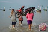 Buruh perempuan menggotong sebuah motor untuk dinaikkan ke atas perahu bermotor, di Pantai Pegagan, Pademawu, Pamekasan, Jatim, Jumat (17/5). Mereka mendapat imbalan Rp5.000 per orang setiap mengangkat satu unit sepeda motor ke perahu penyeberangan. ANTARA FOTO/Saiful Bahri/nym/2013.